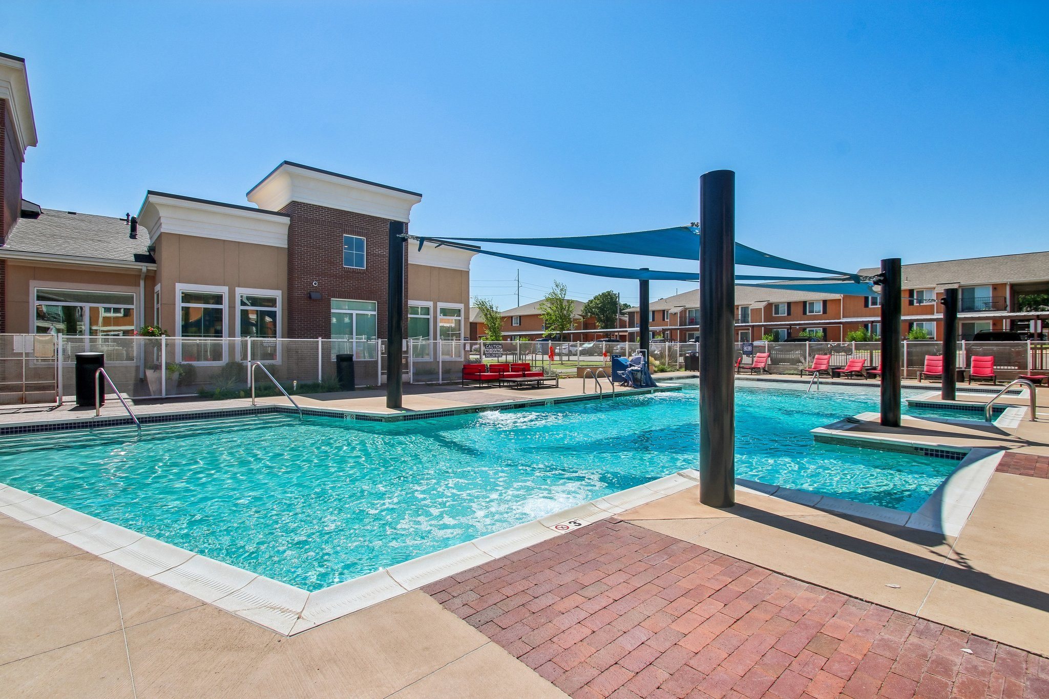 A large outdoor swimming pool with a blue shade structure.